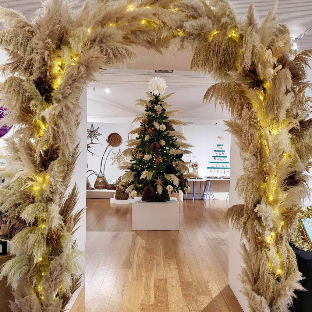 christmas craft arch way out of pampas grass and the Christmas tree in the background