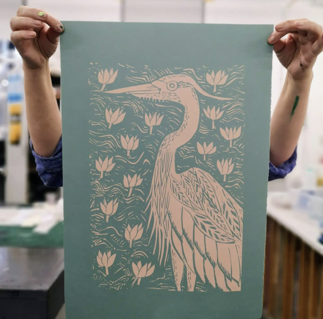 Printing picture of a heron in cream on a green background.
