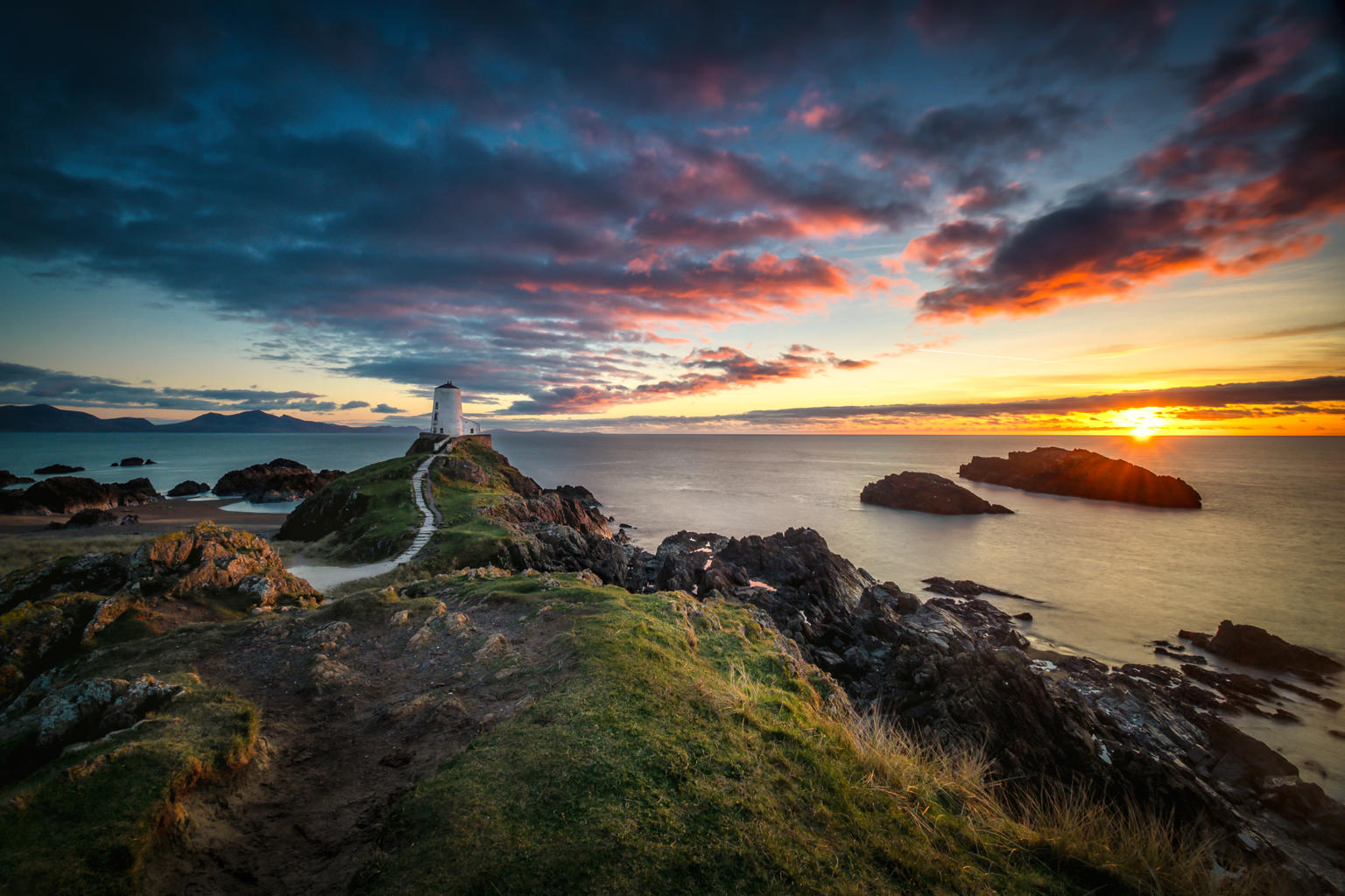 A photograph of Llanddwyn with the sunset in the back