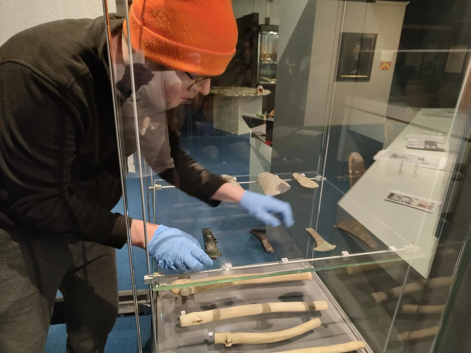 Arwyn placing objects in a glass cabinet in the History Museum.