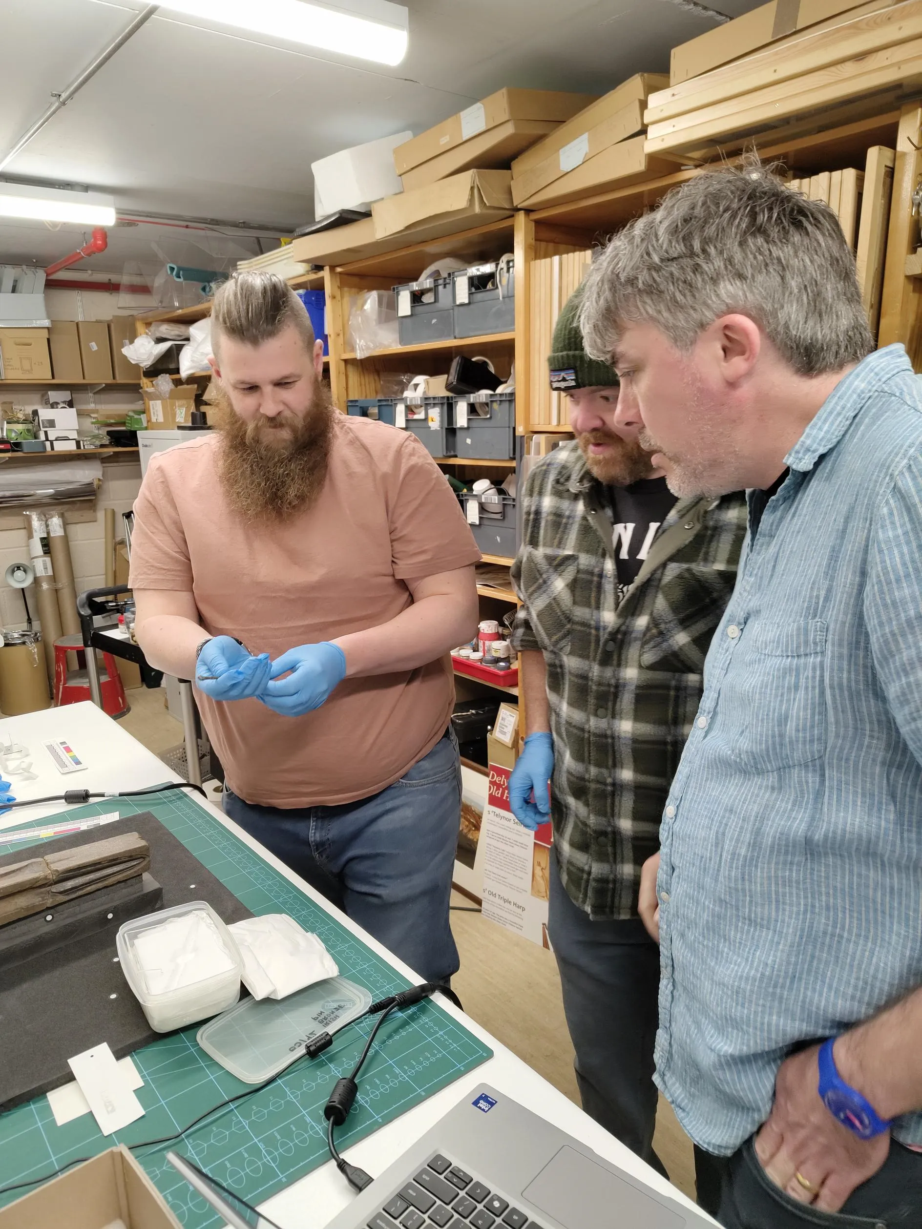 Delwedd y tu ôl i'r llen o ddelio â gwrthrychau o gasgliad Oriel Môn.