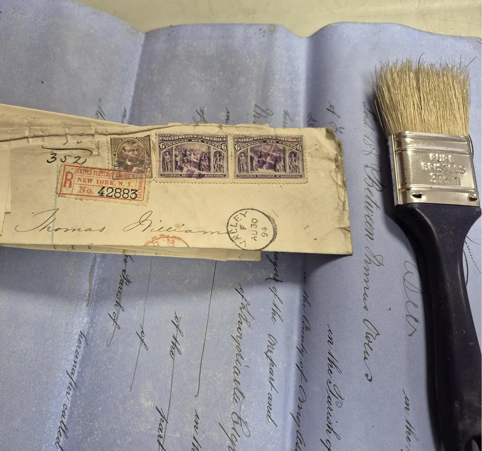 A photograph of a draft will, envelope and paint brush.
