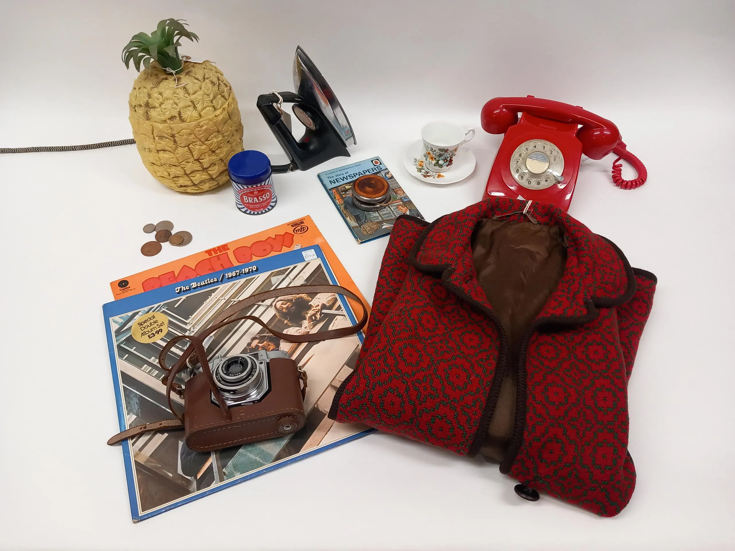 A selection of vintage objects including records, a camera, a jacket, a telephone and an iron.