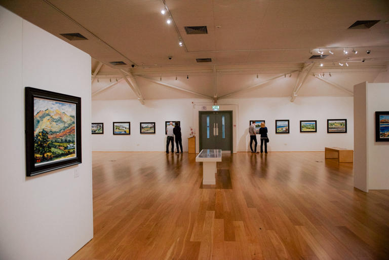 People standing looking at artwork in a gallery.
