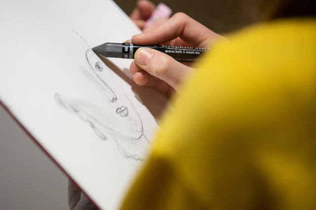 Photograph of a person sketching a face.