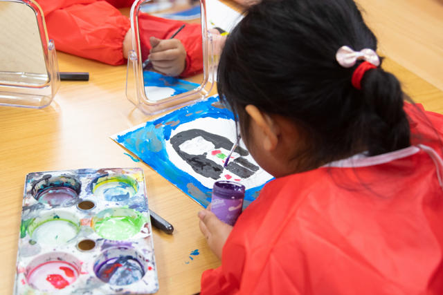 Photograph of a child painting their own portrait.