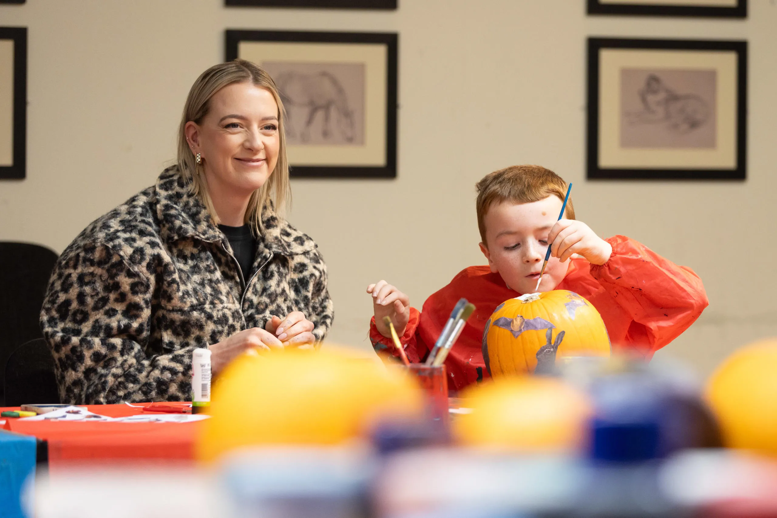 A woman and child sit at a table painting.