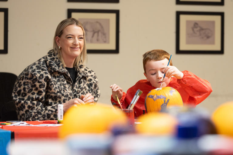 A woman and child sit at a table painting.
