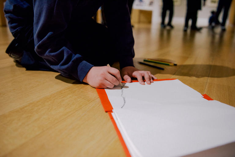 A child drawing on an open sketchbook.