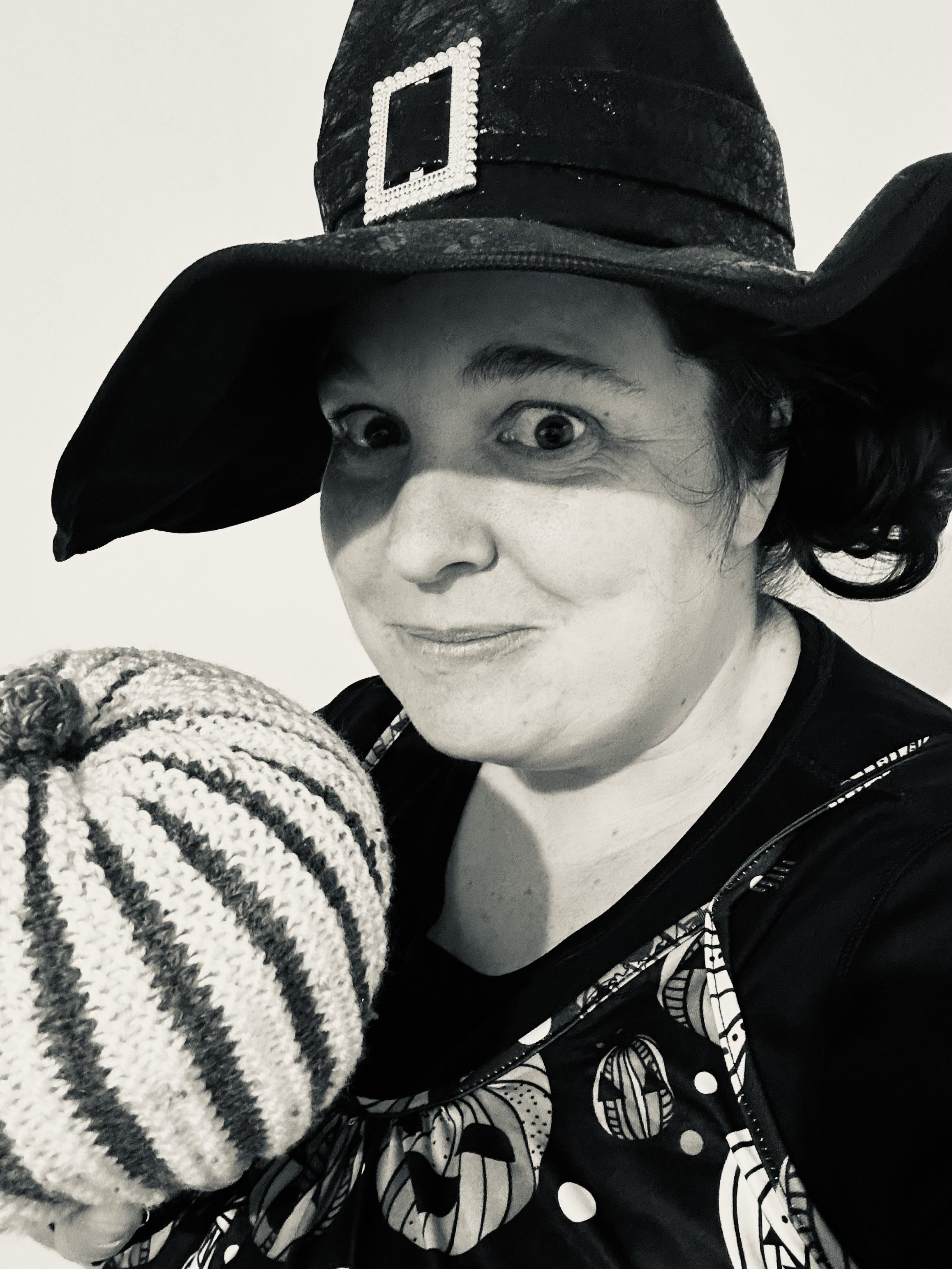 Photograph of Catrin wearing a witch hat and holding a pumpkin.