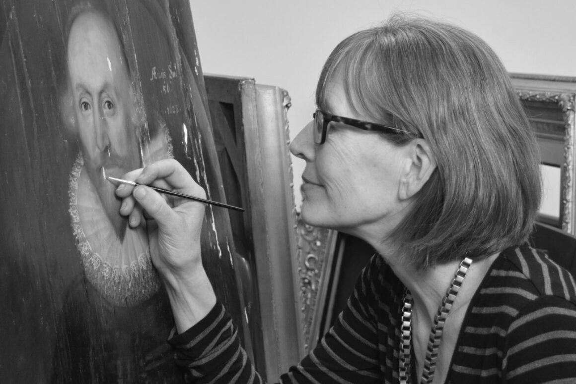 A black and white photograph of Jenny Williamson working on a painting.