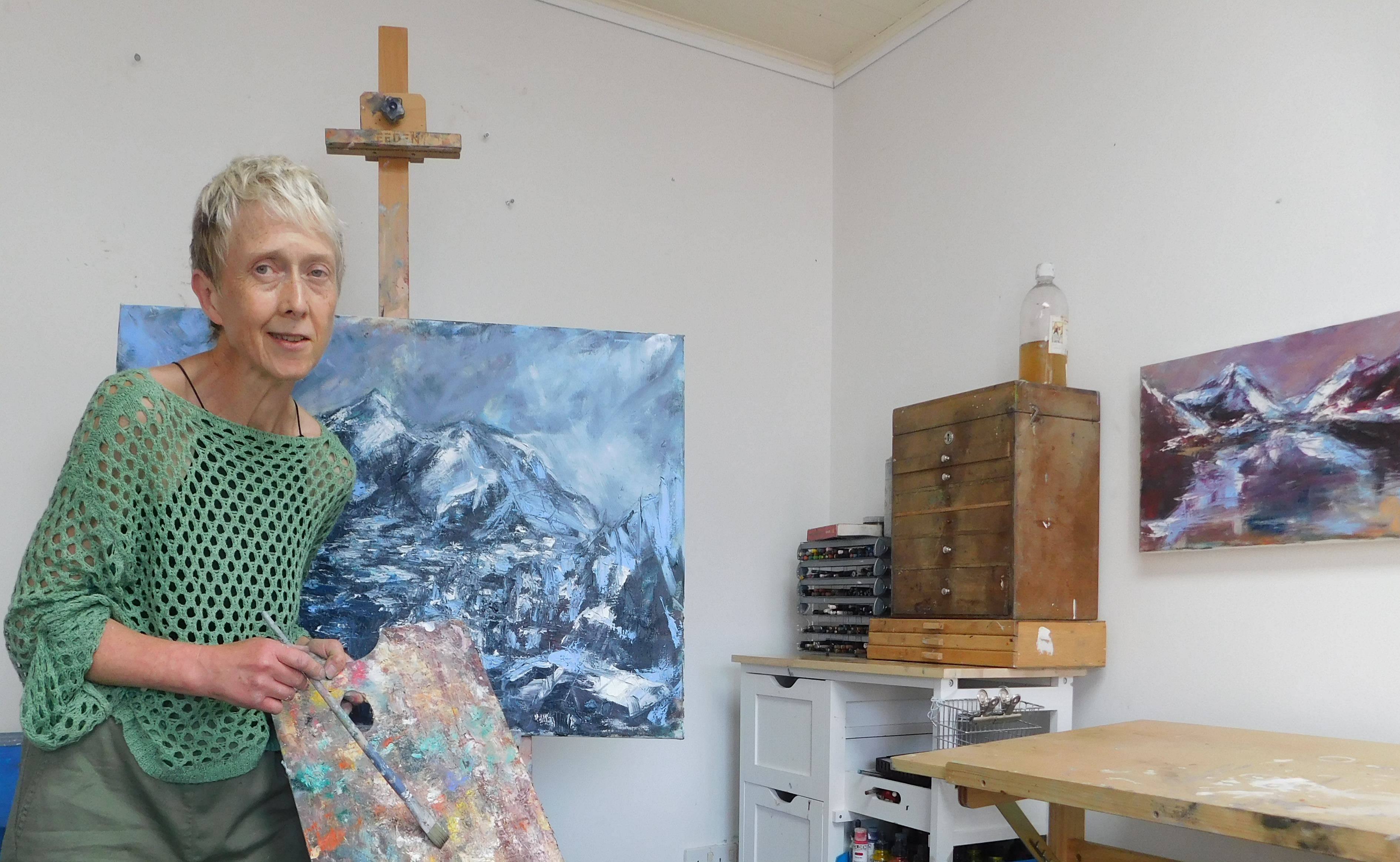 a photograph of Louise Morgan painting in her studio