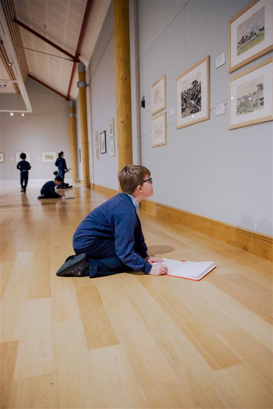 A school pupil sketching in a gallery.