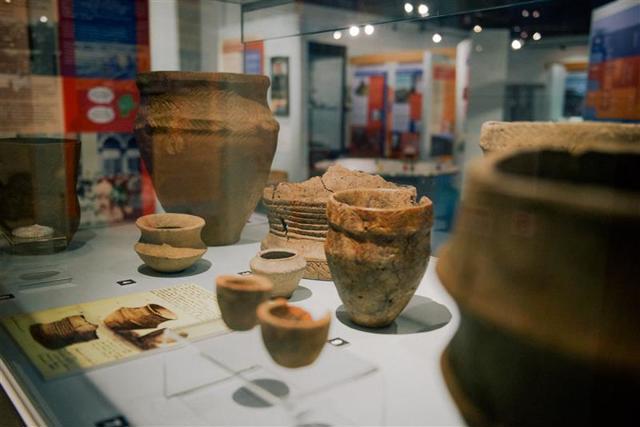 An arrangement of clay pots in a display case.